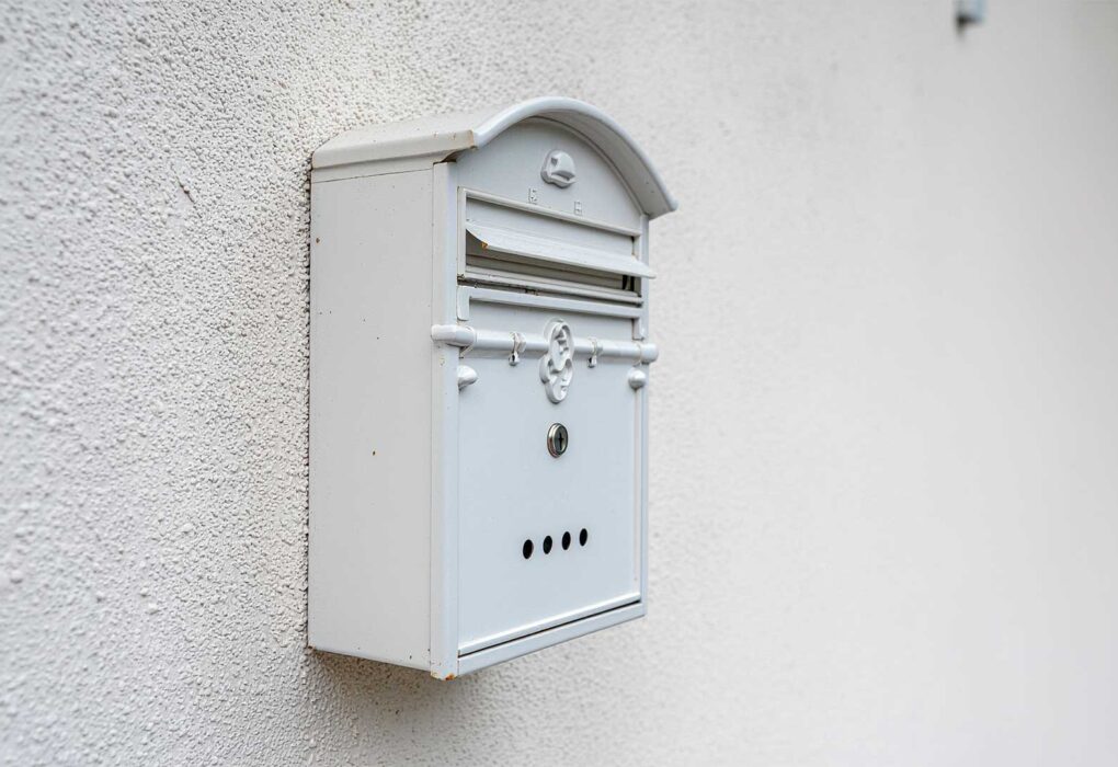 Buzón de correos blanco en pared, simbolizando la sección Cartas al Director de Beniaján al Día