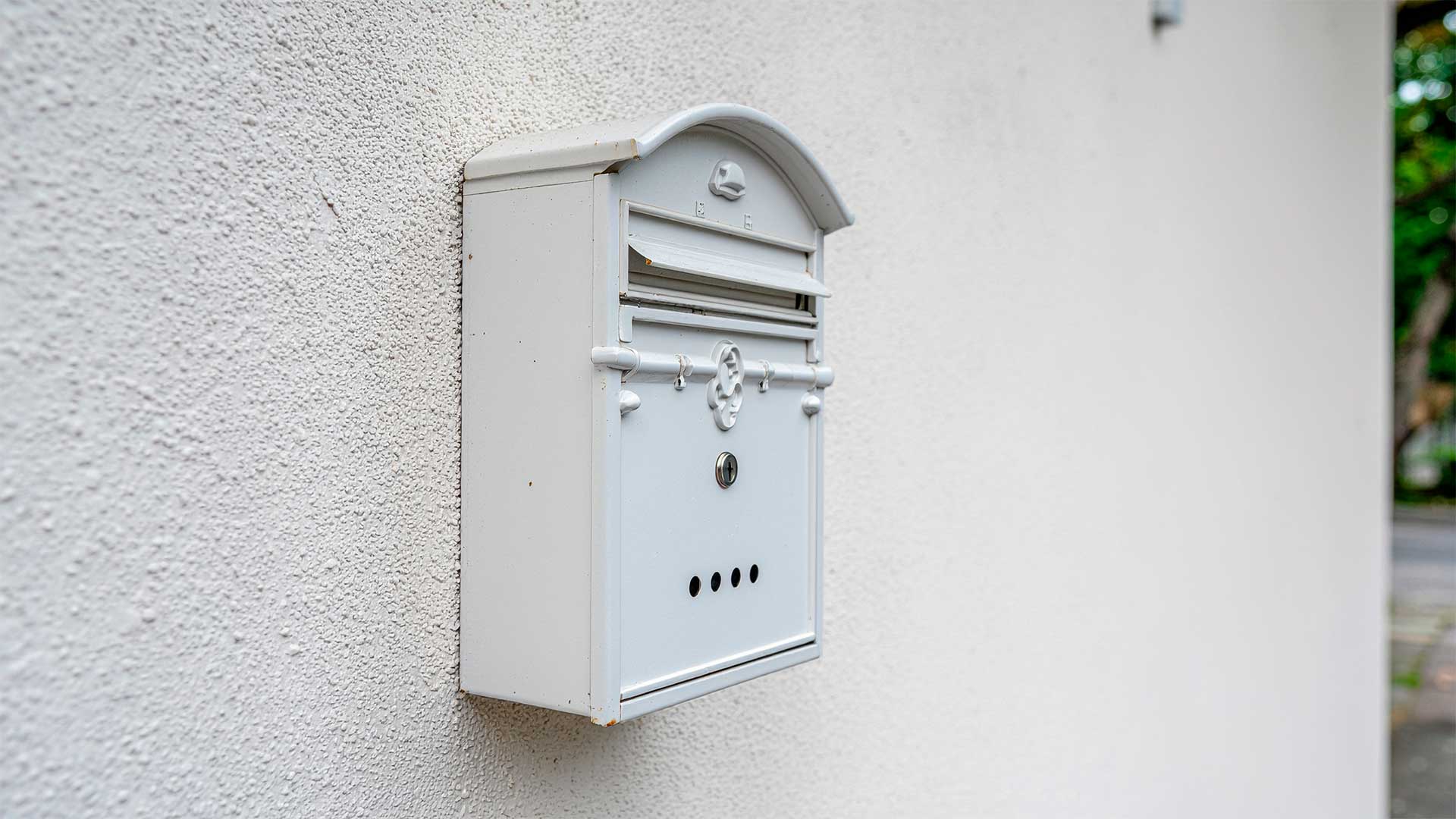 Buzón de correos blanco en pared, simbolizando la sección Cartas al Director de Beniaján al Día