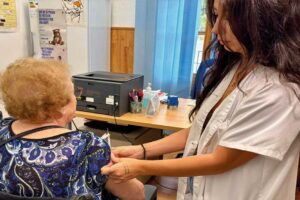 Enfermera inyectando la vacuna de la gripe a una mujer mayor de espaldas en el Servicio de Vacunación Municipal de Murcia.