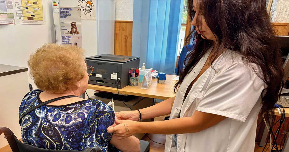 Enfermera inyectando la vacuna de la gripe a una mujer mayor de espaldas en el Servicio de Vacunación Municipal de Murcia.