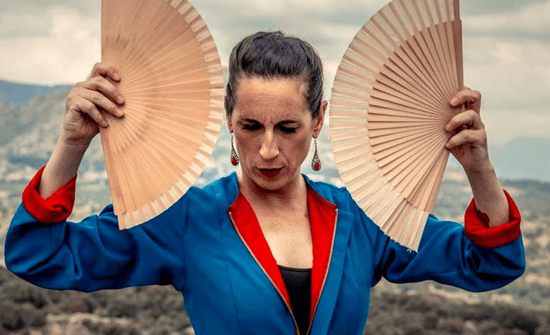 Sara Nieto, bailaora, en pose flamenca con abanicos en ambas manos.