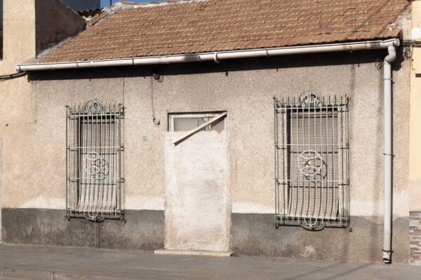 Imagen alegórica de la emergencia habitacional: Casa de planta baja con la puerta principal tapiada con ladrillos, simbolizando la dificultad y el cierre del acceso a la vivienda en el municipio de Murcia.