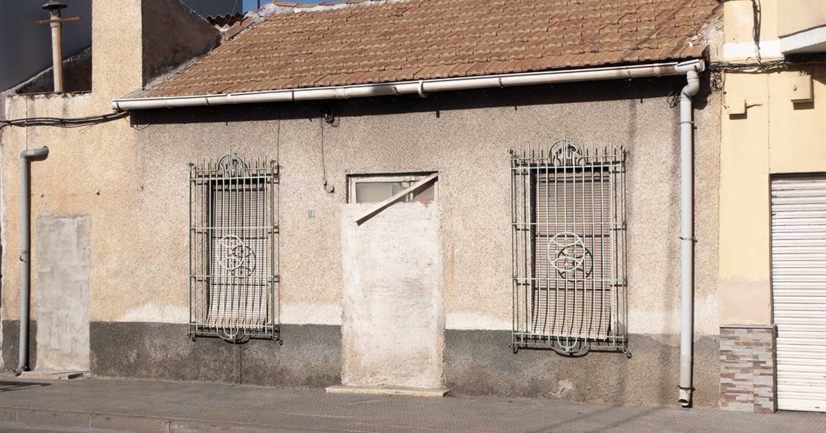 Imagen alegórica de la emergencia habitacional: Casa de planta baja con la puerta principal tapiada con ladrillos, simbolizando la dificultad y el cierre del acceso a la vivienda en el municipio de Murcia.