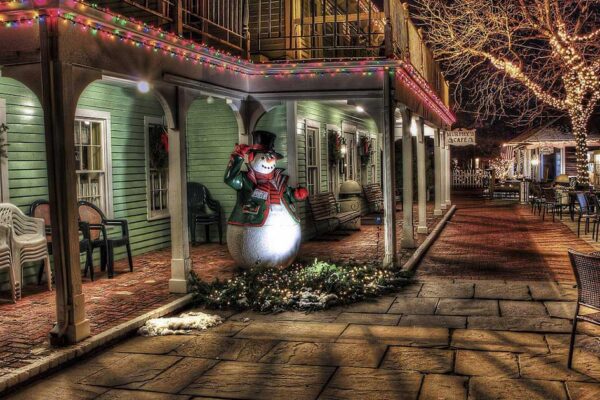 Calle de Los Ramos con una vivienda de madera decorada con luces y motivos navideños; muñeco de nieve en el porche
