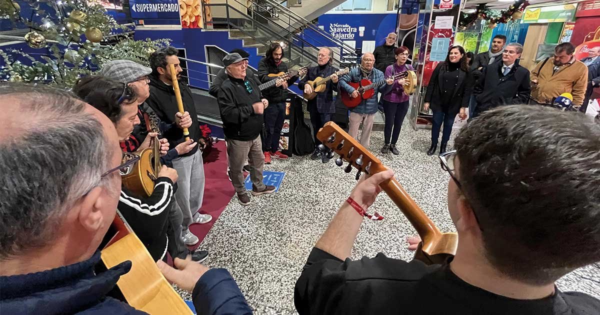 Jóvenes integrantes de una cuadrilla murciana tocando instrumentos y cantando villancicos en una plaza de abastos del centro de Murcia, dinamizando la tradición navideña