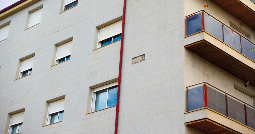 Fachada del edificio Bolero II en la avenida del Palmar, Beniaján, con el hueco de la losa desprendida sobre la acera.