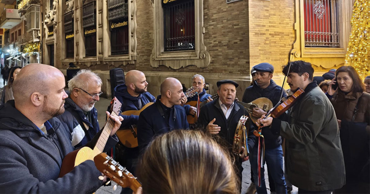 Miembros de la Cuadrilla de Torreagüera tocando la guitarra y cantando aguilandos en la calle.