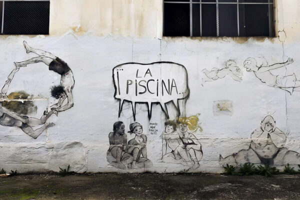 Detalle del mural de Chipola en Beniaján mostrando niños en bañador jugando y nadando en una piscina imaginaria, con la viñeta central que proclama “¡La Piscina!”, reflejando la reivindicación histórica de la pedanía.