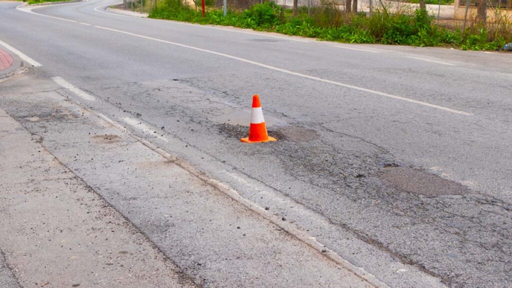 Cono de tráfico señalizando un bache persistente en la avenida de El Palmar, Beniaján (Murcia). Ejemplo de la "cultura del cono": señalización provisional que dura meses sin reparación real en pedanías.