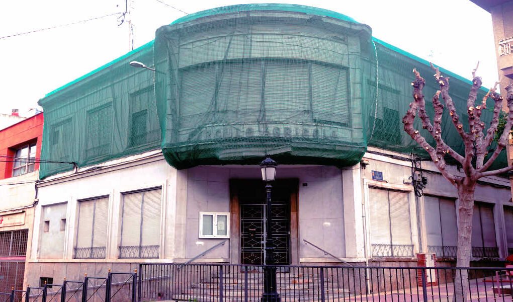 Fachada del Casino Agrícola de Torreagüera con lona verde en el piso superior para proteger la vía pública de posibles desprendimientos.