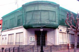 Fachada del Casino Agrícola de Torreagüera con lona verde en el piso superior para proteger la vía pública de posibles desprendimientos.