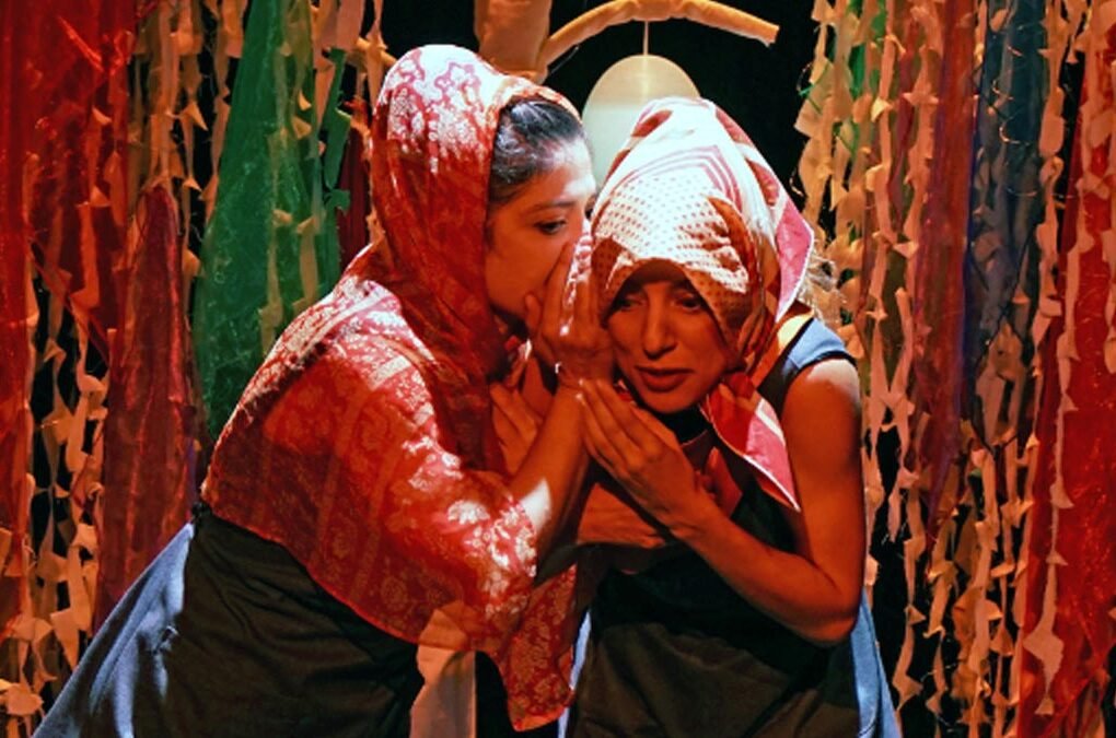 Dos actrices de Tarambana Teatro Aída de la Cruz y Camila Puelma en el escenario de Pañuelos rodeadas de pañuelos y telas colgantes multicolores creando un ambiente sensorial para bebés y primera infancia