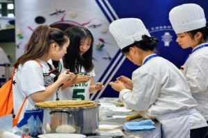 Participantes coreanas en la feria Seoul Food and Hotel 2026 en Corea del Sur, cocineras y profesionales interactuando con productos alimentarios en un stand de exposición