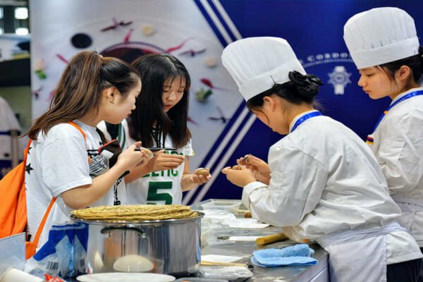 Participantes coreanas en la feria Seoul Food and Hotel 2026 en Corea del Sur, cocineras y profesionales interactuando con productos alimentarios en un stand de exposición