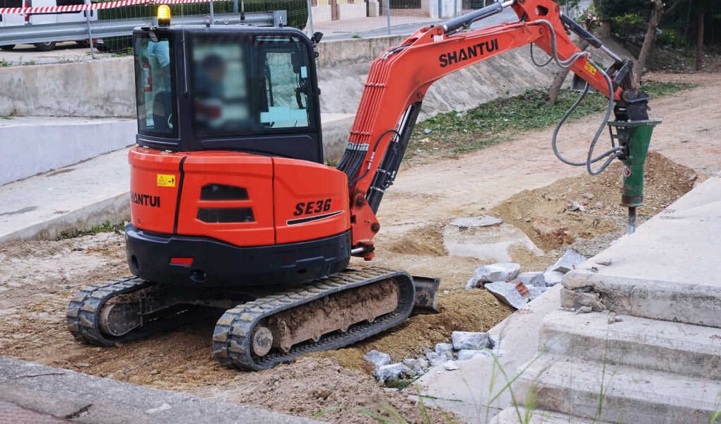 Máquina de oruga con brazo y pico hidráulico demoliendo una rampa de hormigón en las obras de la Vía Verde de San José de la Vega, Murcia.