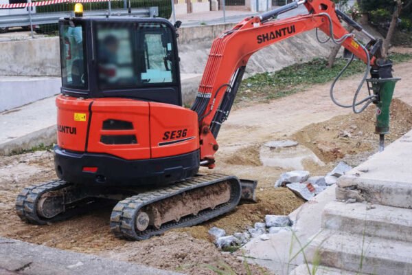 Máquina de oruga con brazo y pico hidráulico demoliendo una rampa de hormigón en las obras de la Vía Verde de San José de la Vega, Murcia.