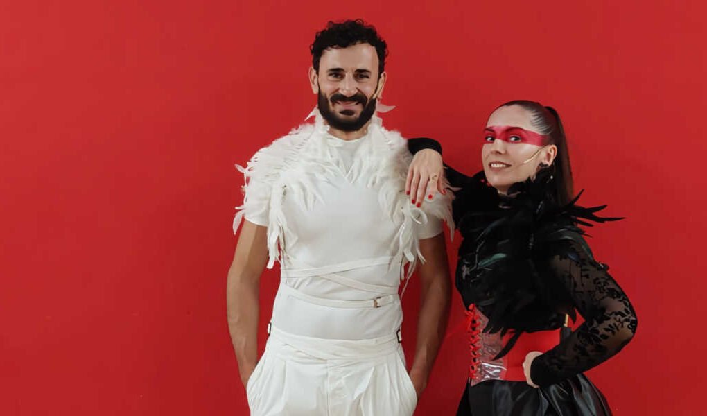 Dos actores posando frente a un fondo rojo burdeos en la obra De amor y desamor de la Coral Vía Musicalis para la Muestra de Teatro Edmundo Chacour en Beniaján.