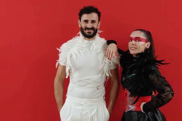 Dos actores posando frente a un fondo rojo burdeos en la obra De amor y desamor de la Coral Vía Musicalis para la Muestra de Teatro Edmundo Chacour en Beniaján.