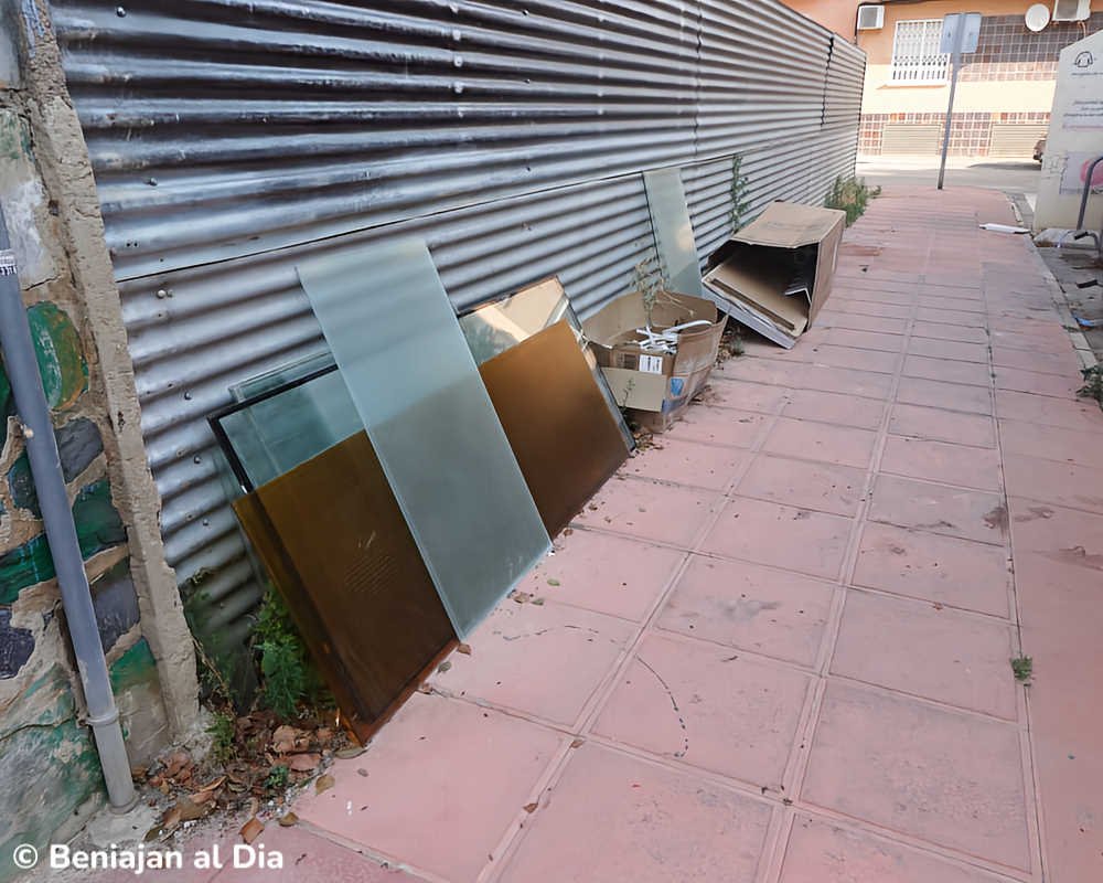 Cristales de gran tamaño y cajas de cartón depositados sobre la acera de la calle Gloria Fuertes, en Beniaján.