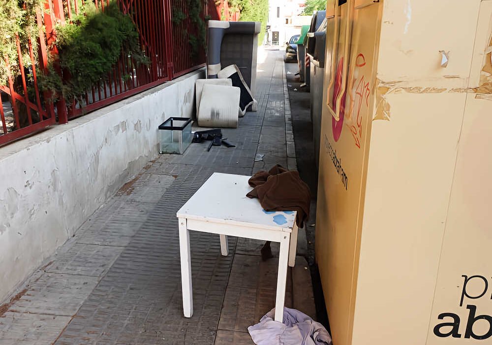 Muebles, colchones y otros enseres abandonados junto a una acera en Beniaján, Murcia.