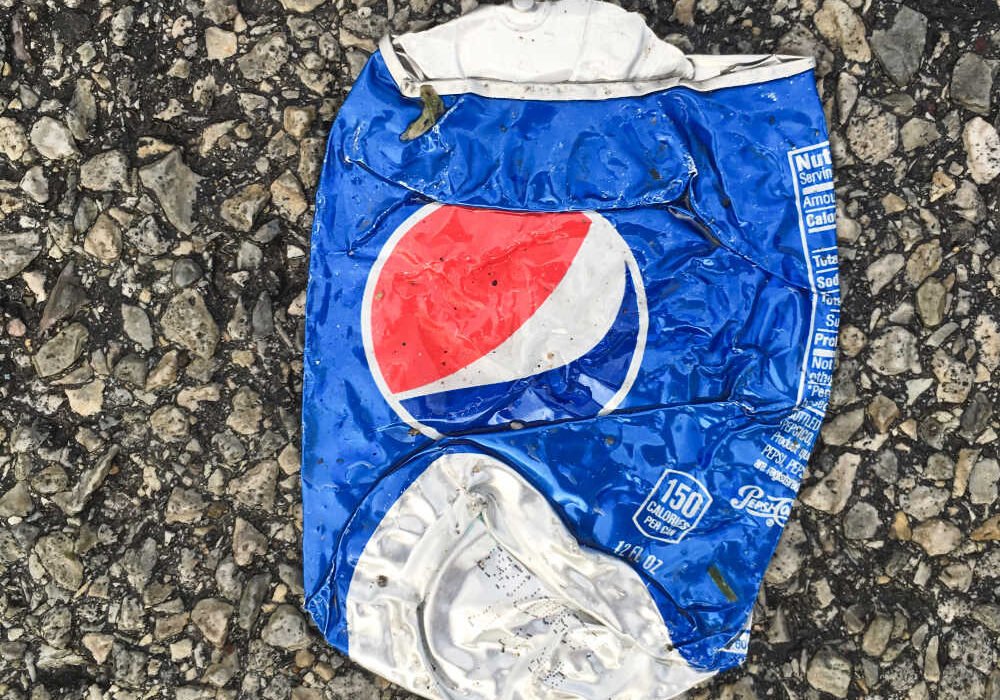 Lata de refresco de aluminio aplastada sobre el suelo, símbolo del reciclaje de envases.