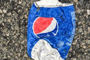 Lata de refresco de aluminio aplastada sobre el suelo, símbolo del reciclaje de envases.