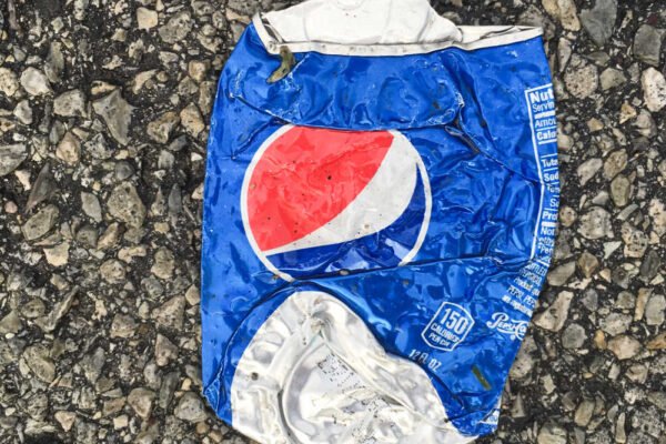 Lata de refresco de aluminio aplastada sobre el suelo, símbolo del reciclaje de envases.