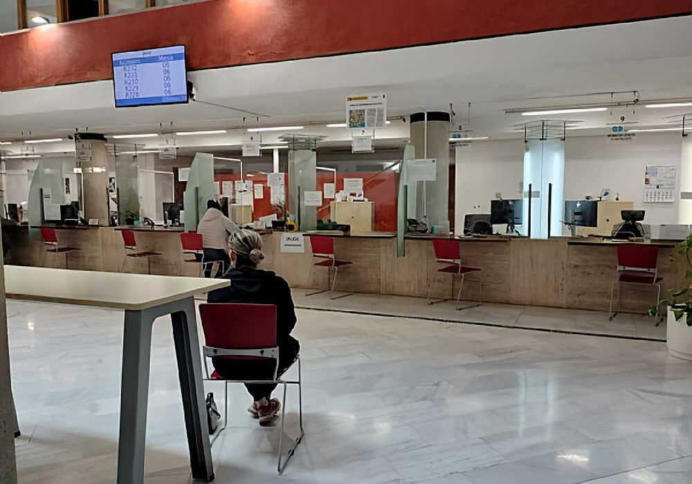 Oficina municipal vacía de atención al ciudadano en Murcia con cartel de Se Necesita Cita Previa en las ventanillas