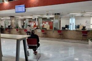 Oficina municipal vacía de atención al ciudadano en Murcia con cartel de Se Necesita Cita Previa en las ventanillas