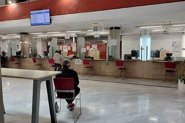Oficina municipal vacía de atención al ciudadano en Murcia con cartel de Se Necesita Cita Previa en las ventanillas