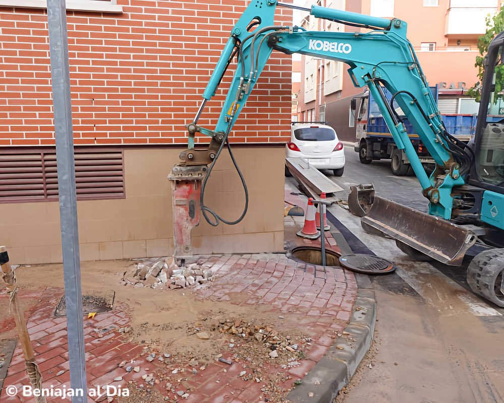 Maquinaria pesada abre una zanja para reparar una rotura en la red general de agua en la calle Federico Giráo de Beniaján.