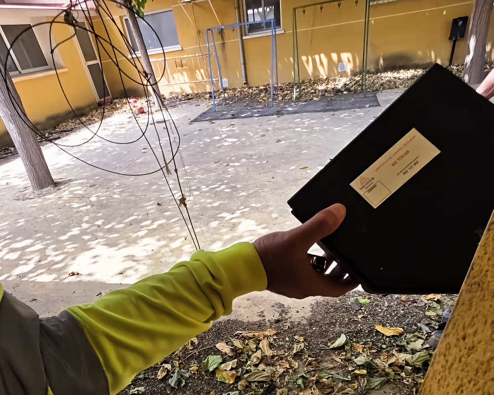 Mano de un operario colocando un dispositivo de desratización en la antigua guardería de Beniaján.
