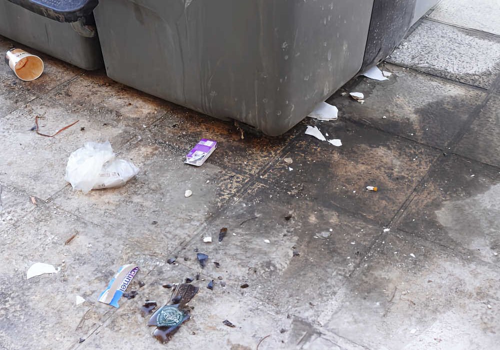 Contenedores de basura insalubres en Beniaján, Murcia, con residuos y suciedad acumulada en el suelo