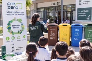 Escolares participan en una actividad de educación ambiental sobre reciclaje y economía circular en un colegio de Murcia junto a contenedores de residuos