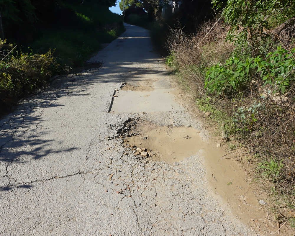 Sucesión de baches, socavones con tierra y asfalto agrietado en el Camino de San Antón en El Bojar, Beniaján