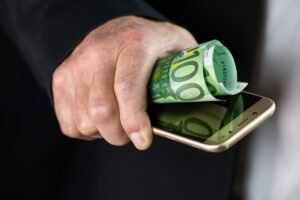Billete de 100 euros junto a un móvil, en referencia a la devolución del dinero por estafas bancarias online.