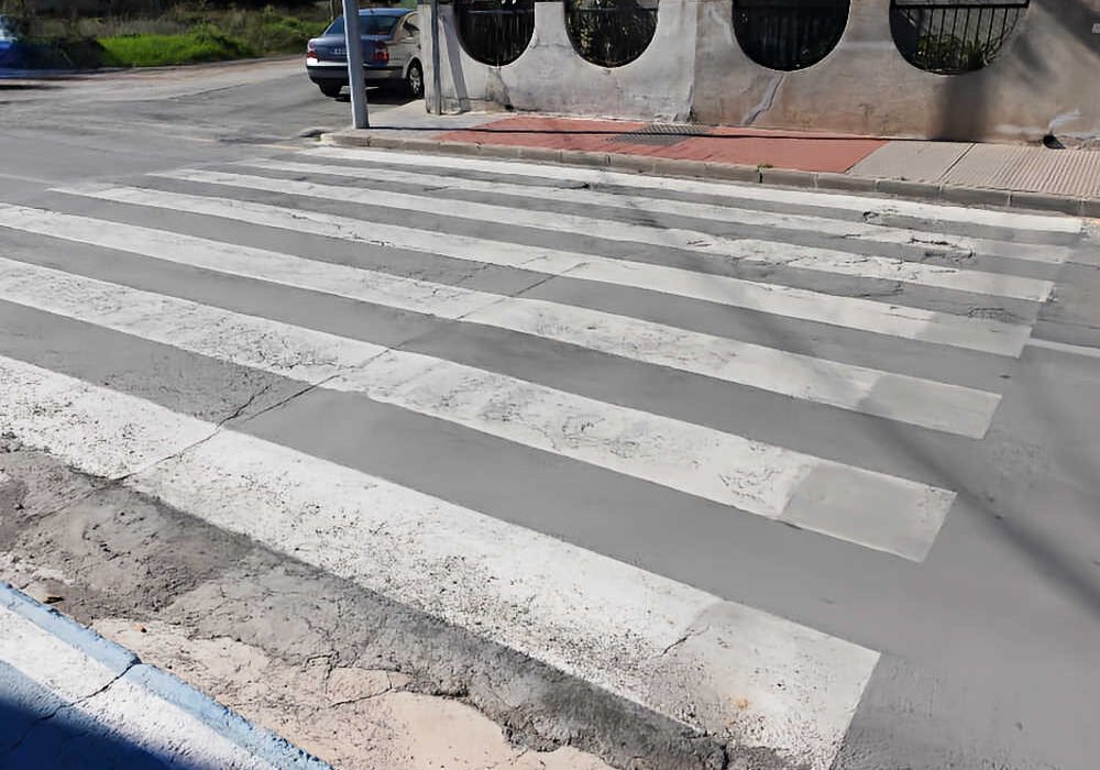 Paso de peatones inaccesible en San José de la Vega (Murcia) con bordillo vertical y calzada deteriorada sin rebaje a cota cero.